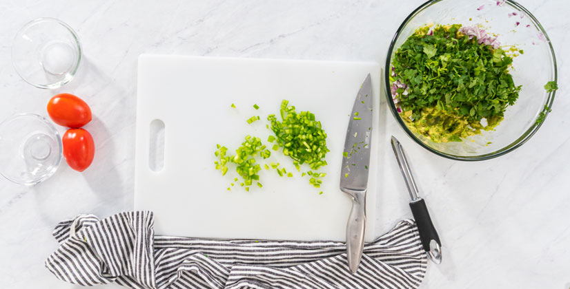 Flat lay. Cutting ingredients on a white cutting board to make classic guacamole dip.