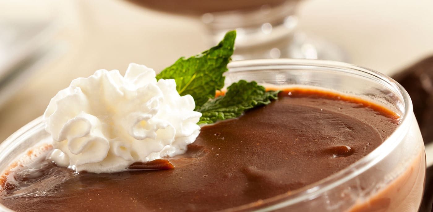 Fancy glass cup of chocolate, peanut butter pudding with a dollop of whipped cream and a mint sprig