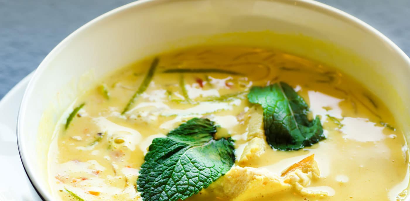 Bowl of curry soup with fresh basil on top