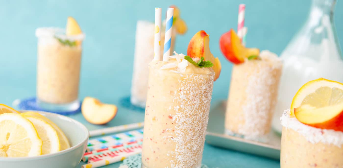 Tropical smoothies with apricot on rim of glass and colorful straws