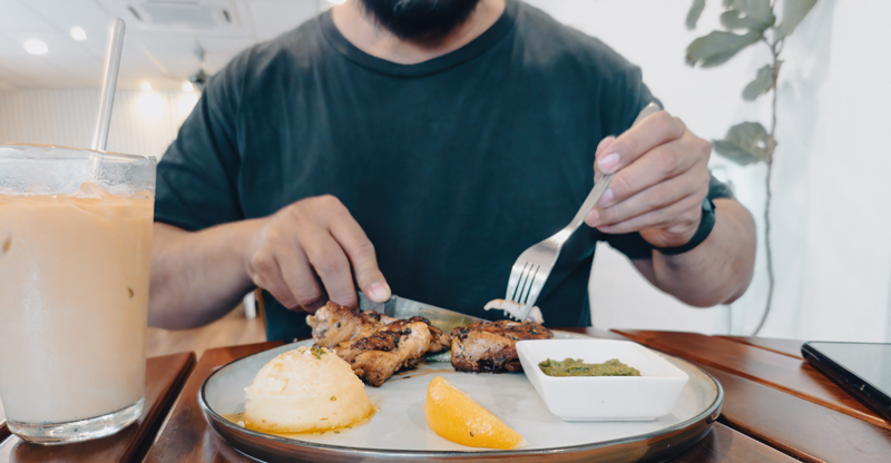 a-man-is-eating-chicken-grilled-served-on-the-plate_web