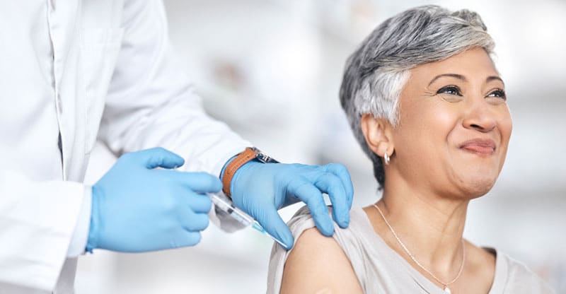 Adult Immunizations Heathcare doctor providing vaccine to mature happy woman.