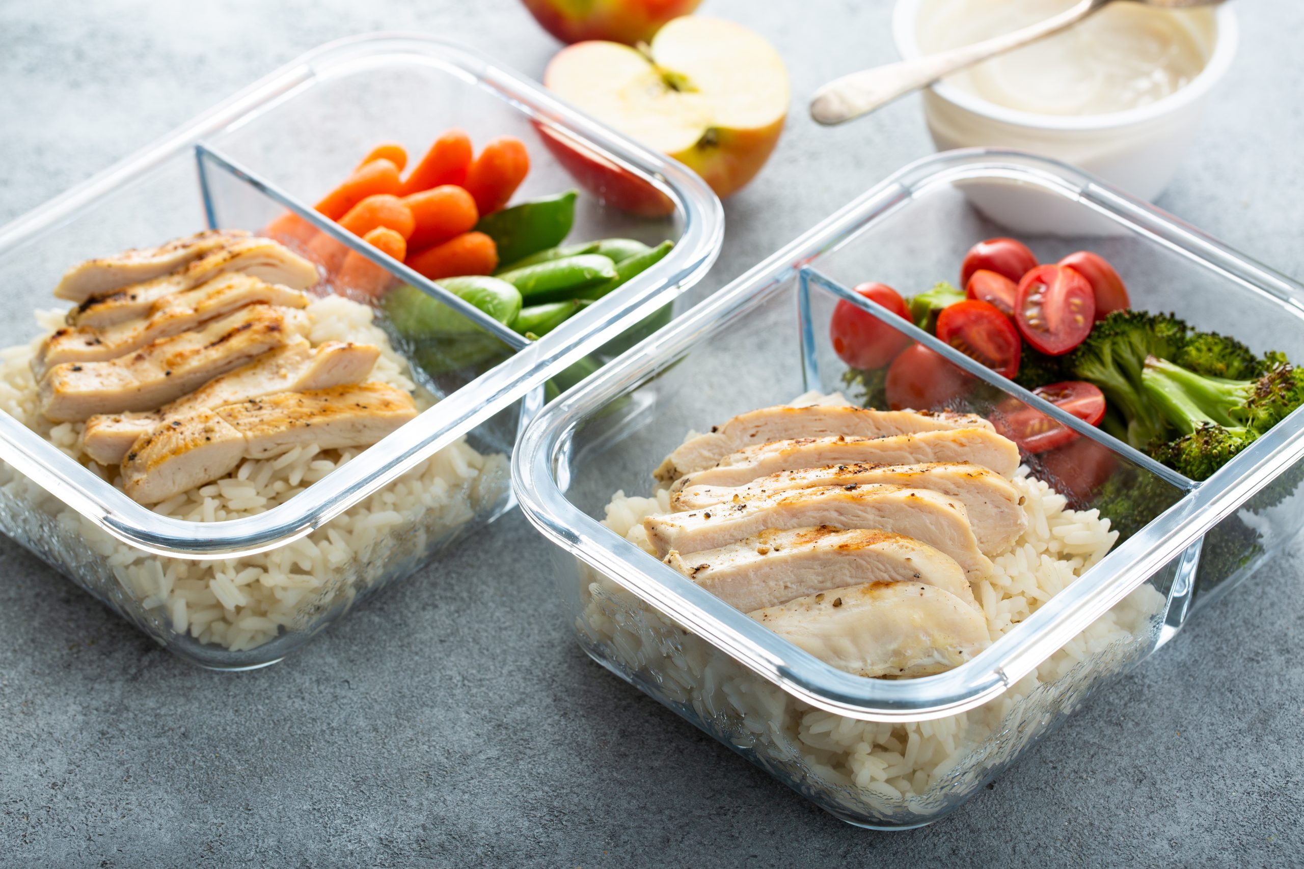 Meal prep containers with healthy lunch to go for work or school with grilled chicken, rice and vegetables.